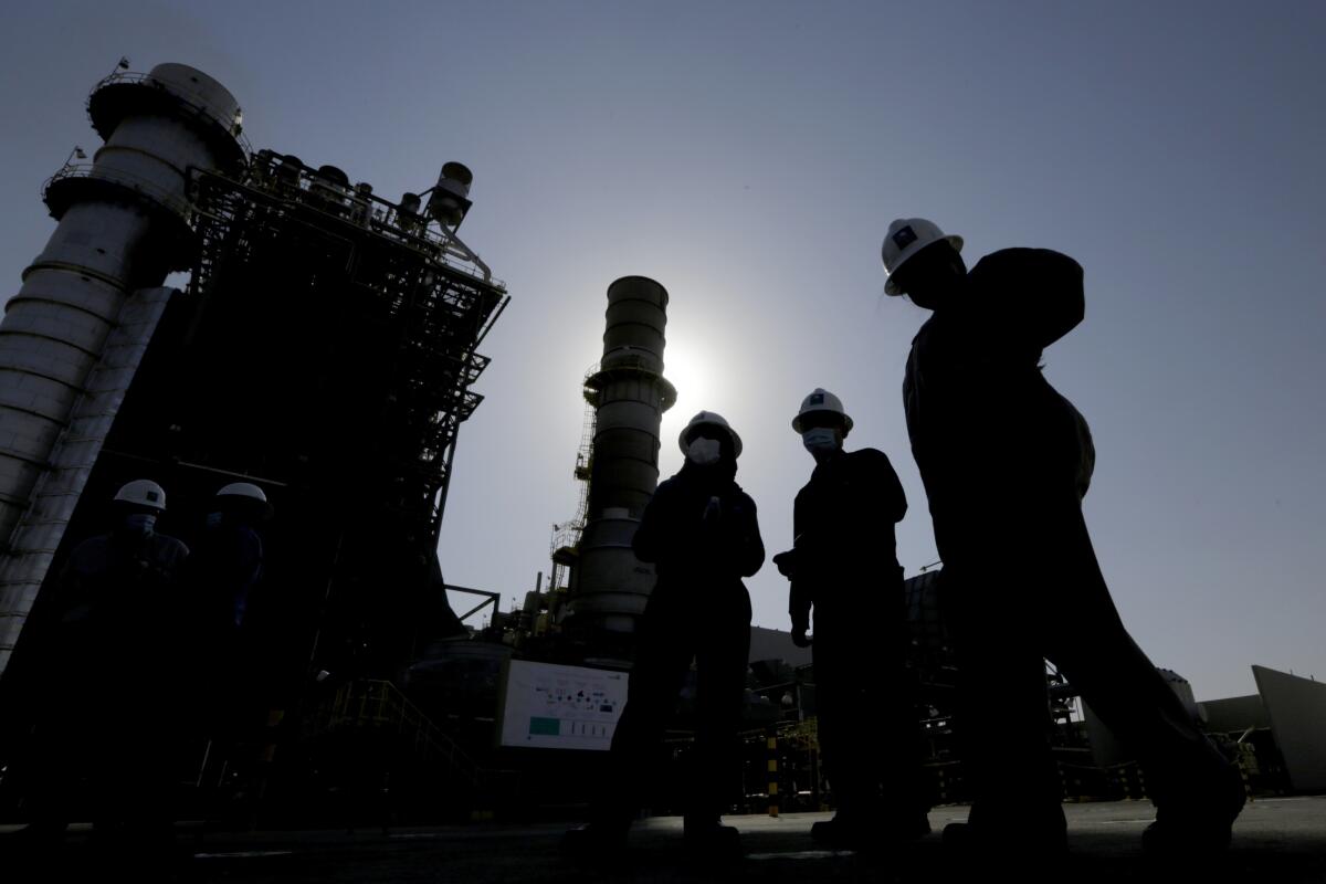 Ingenieros de la petrolera estatal saudí Aramco caminan frente a un generador de turbina de gas 