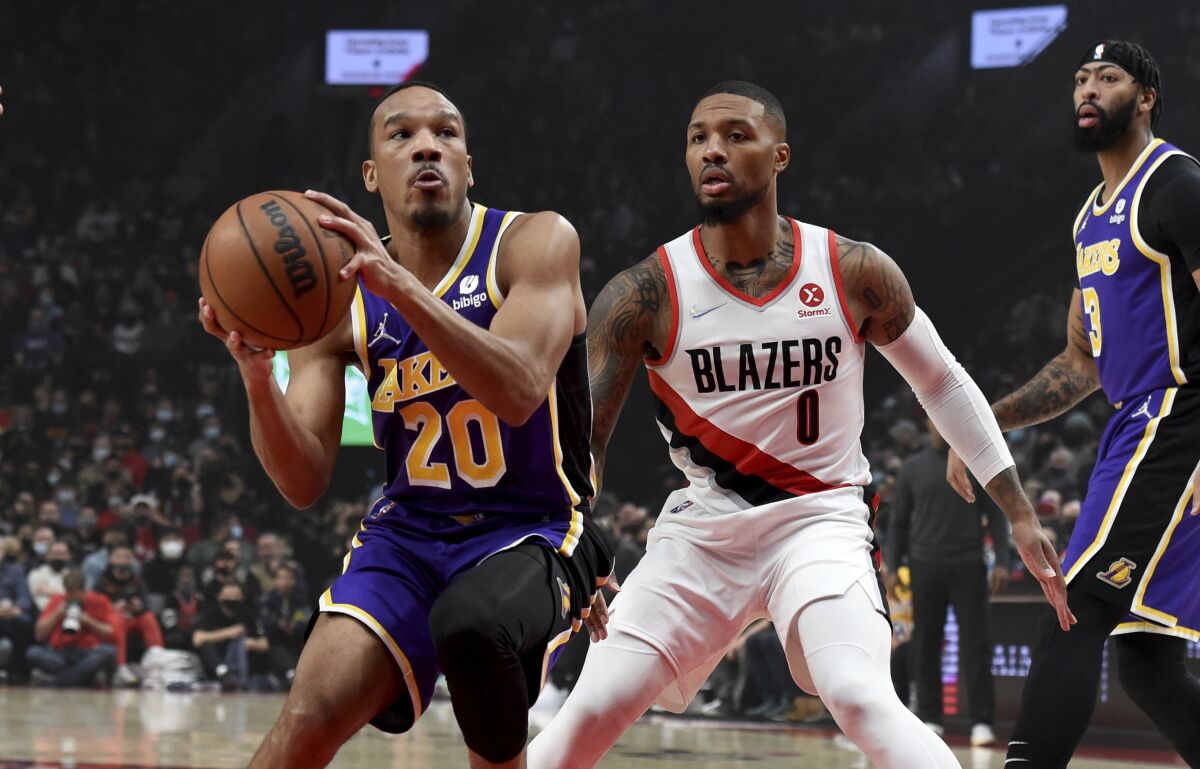 Los Angeles Lakers guard Avery Bradley, left, drives to the basket on Portland Trail Blazers guard Damian Lillard during the first half of an NBA basketball game in Portland, Ore., Saturday, Nov. 6, 2021. (AP Photo/Steve Dykes)