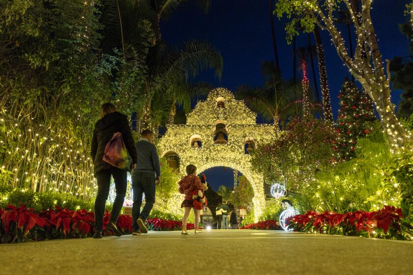 RIVERSIDE, CA - NOVEMBER 10, 2023: Guests walk along the entry way at the historic Mission Inn decorated with some of its extravagant holiday lights on November 10, 2023 in Riverside, California.(Gina Ferazzi / Los Angeles Times)