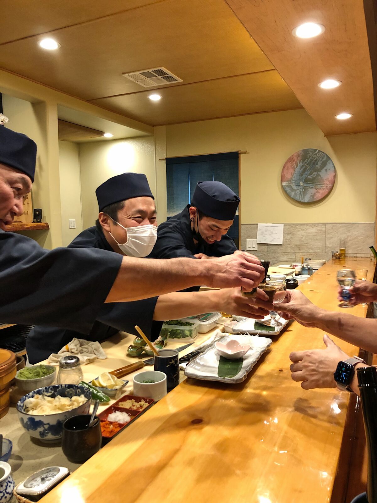 Soichi Kadoya sharse a toast with customers at Soichi Sushi in University Heights.