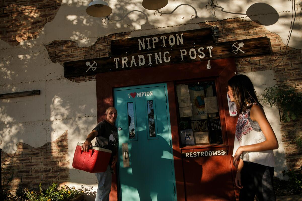 Carl Cavaness and Kiera Freeman joke around outside the trading post in Nipton, Calif.