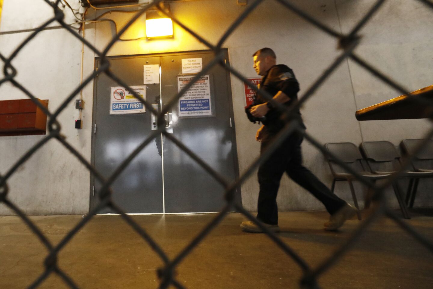 A law enforcement officer walking behind a chain-link fence