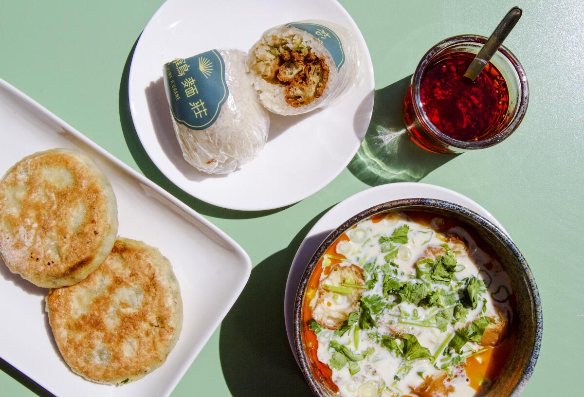 An overhead photo of fan tuan, savory soy milk, and chive-and-egg pockets atop a green table.