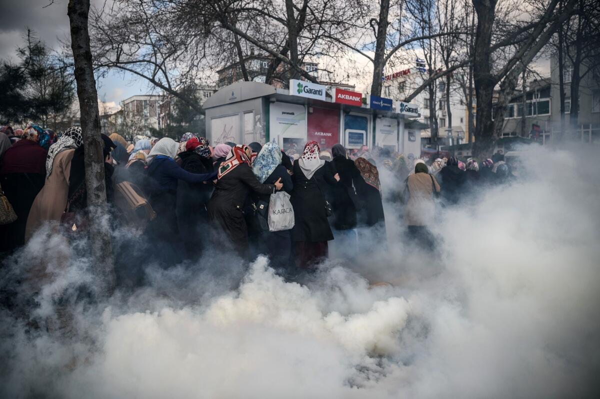 Smoke rises near a group of women as Turkish anti-riot police officers use tear gas to disperse supporters in front of the headquarters of the Turkish daily newspaper, Zaman, in Istanbul after Turkish authorities seized the headquarters in a midnight raid.