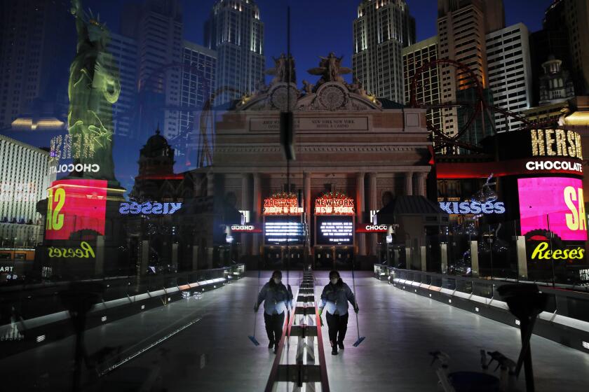 In this April 18, 2020, photo, a lone worker wearing a mask cleans a pedestrian walkway devoid of the usual crowds as casinos and other business are shuttered due to the coronavirus outbreak in Las Vegas. Nevada's governor closed the glitzy casinos and nightlife attractions in mid-March, leaving much of the famous gambling mecca empty, barricaded and abandoned. (AP Photo/John Locher)