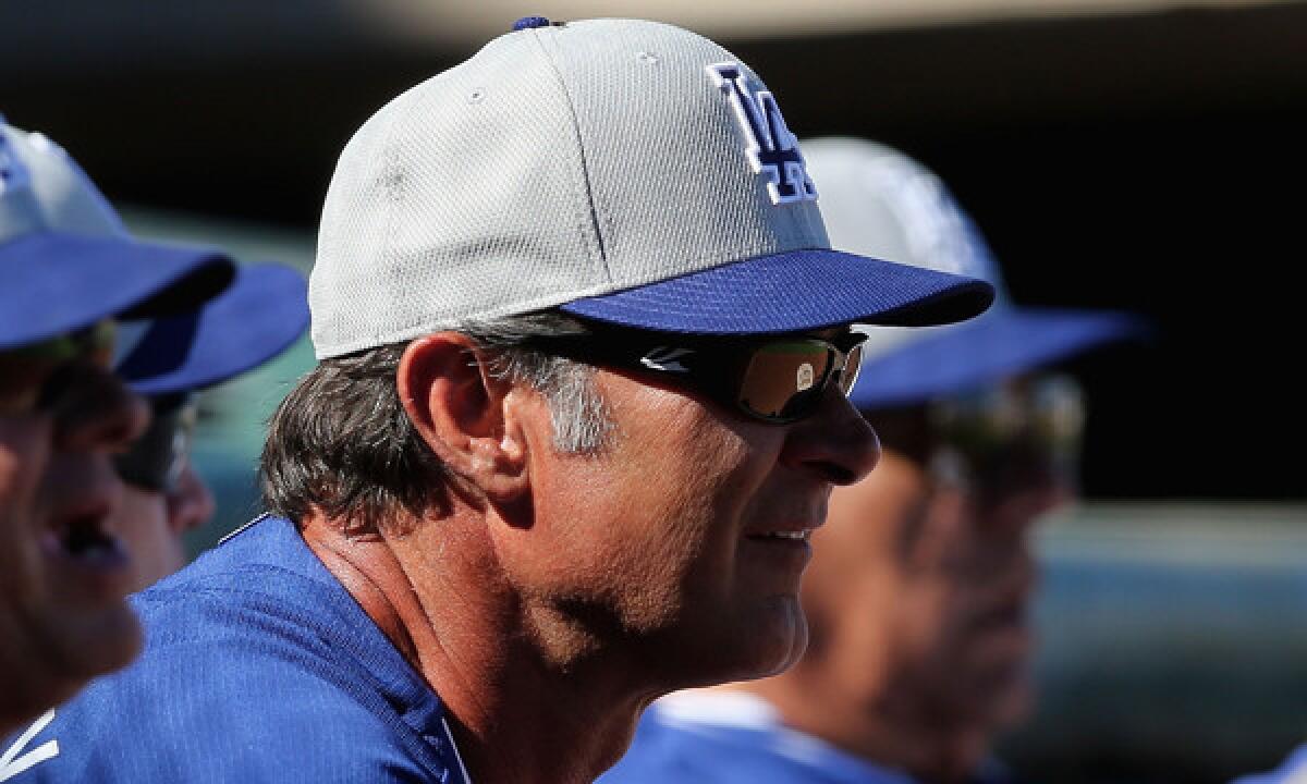 Dodgers Manager Don Mattingly looks on during Saturday's Cactus League game against the Texas Rangers. Mattingly, who has left Dodgers camp because of a death in his family, is expected to rejoin the team Friday.