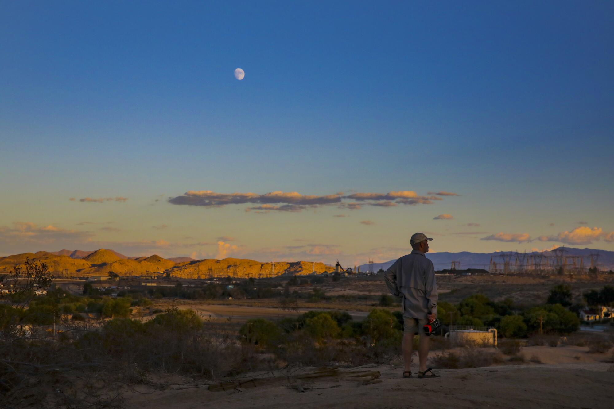 A man scans a desert landscape filled with long shadows.