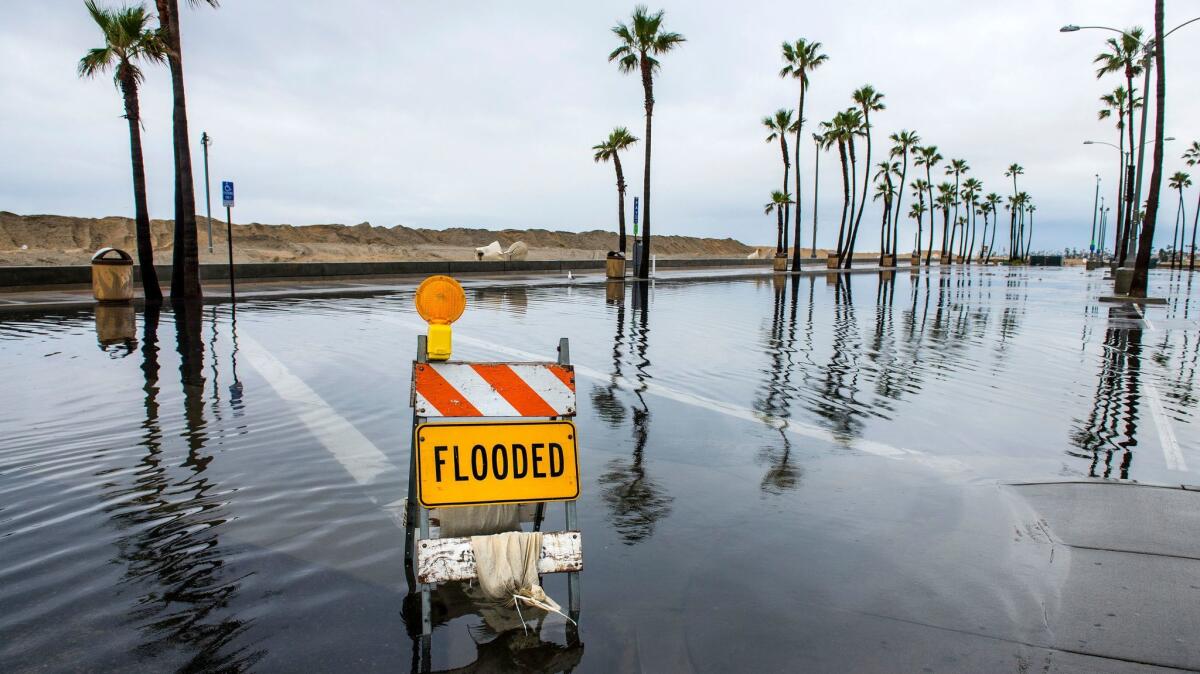 Flooding puts a parking lot near the Balboa Pier in Newport Beach out of commission. A new study finds that rising sea levels will double the risk of flooding along the West Coast and elsewhere.
