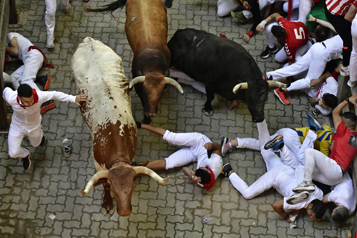 Corredores caen al suelo durante un encierro de las Fiestas de San Fermín en Pamplona, en el norte de España