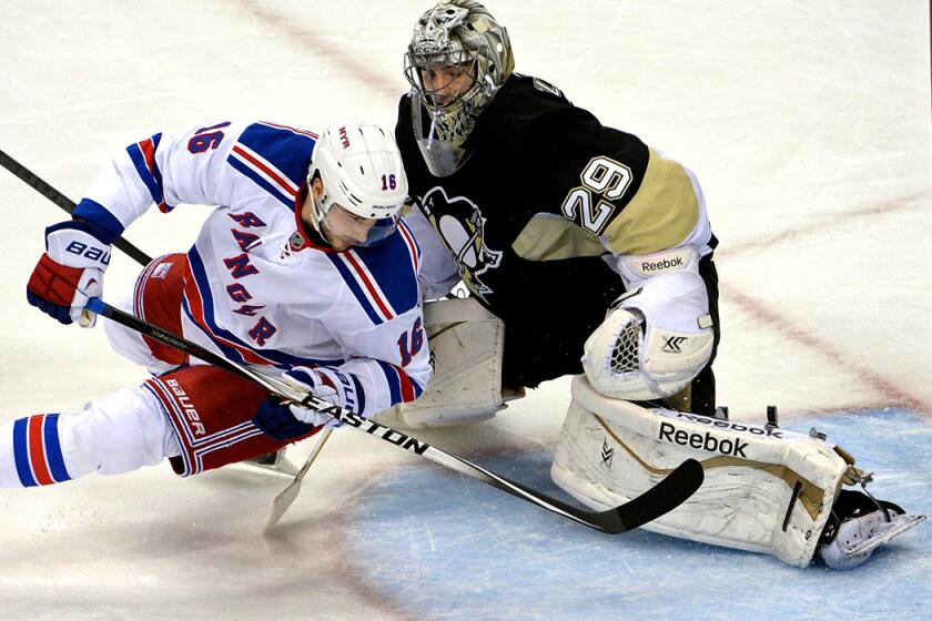 Rangers forward Derick Brassard gets the puck past Penguins goalie Marc-Andre Fleury as he falls to the ice for goal in the first period Friday night.