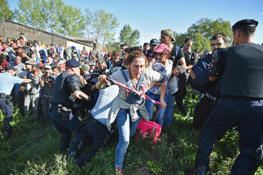 Migrants force their way through police lines at the Tovarnik, Croatia, station to board a train bound for Zagreb, Croatia, on Thursday.