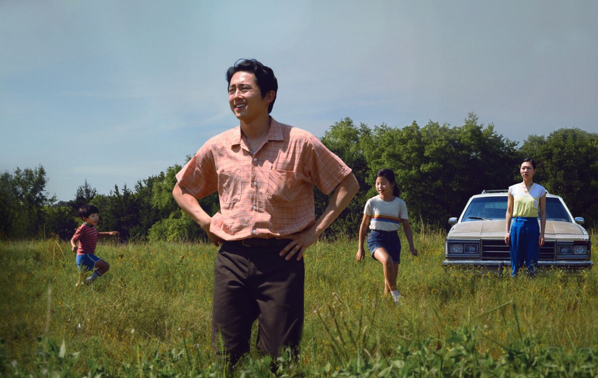 Steven Yeun stands in a field with his movie family in a scene from "Minari."