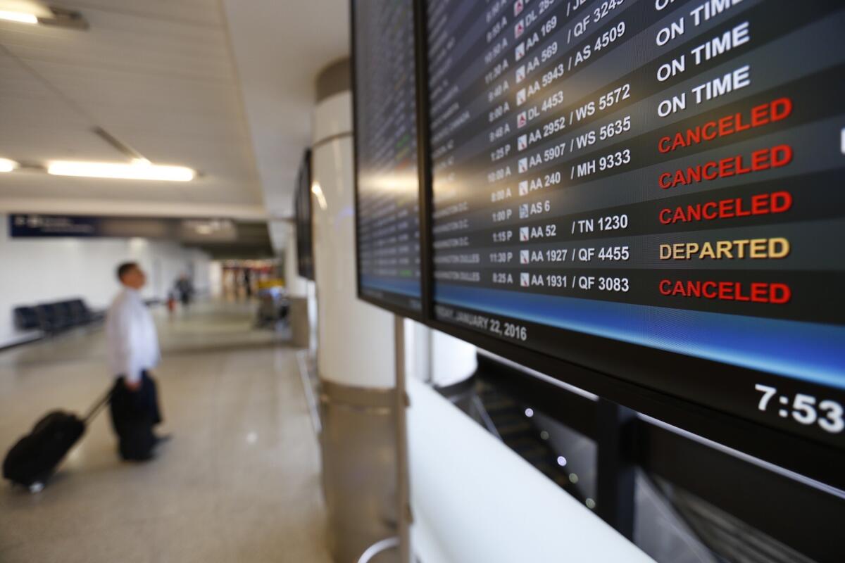 Flight status monitors at Los Angeles International Airport show cancellations Friday morning.