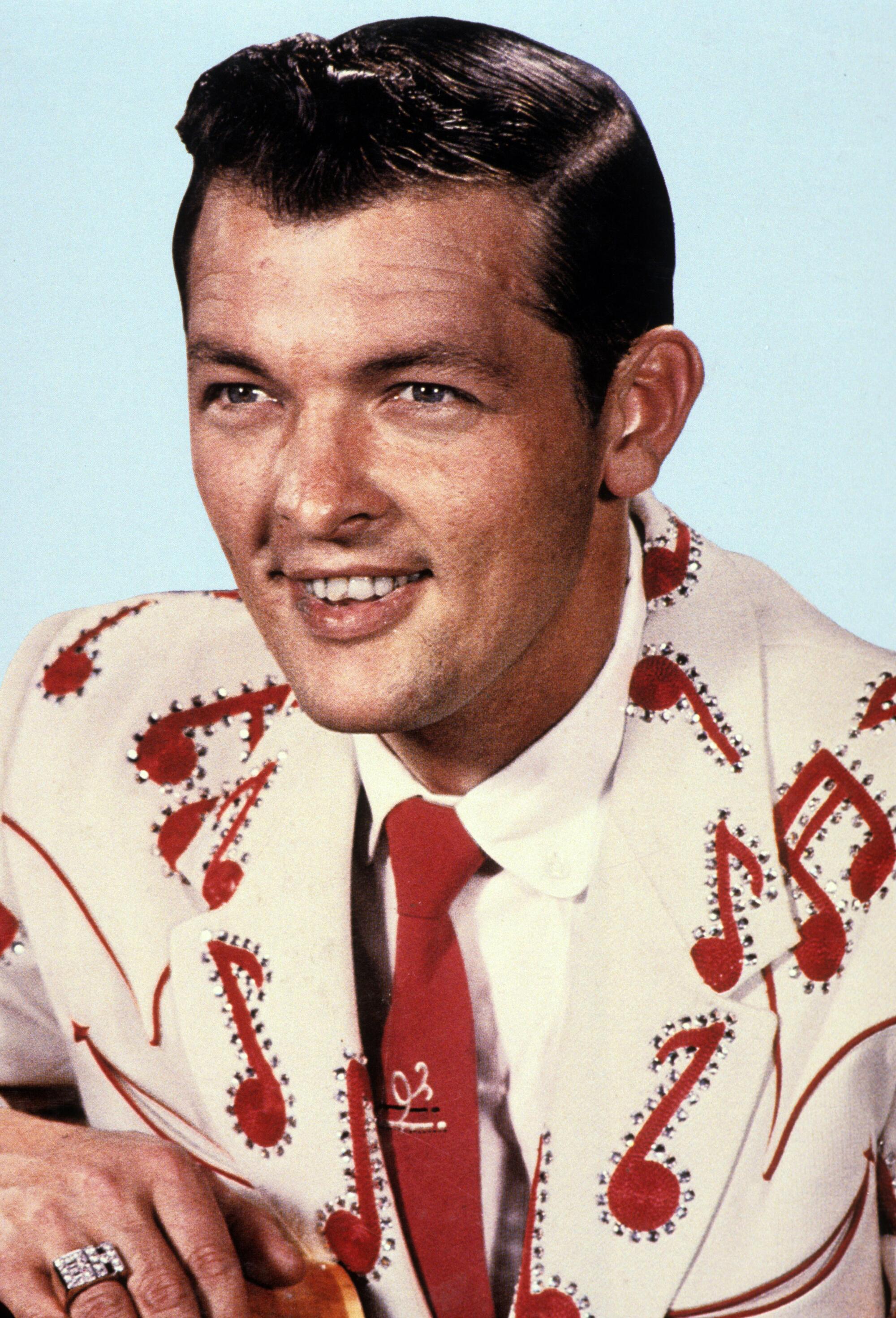 An early rock 'n' roll singer in a suit festooned with musical notes