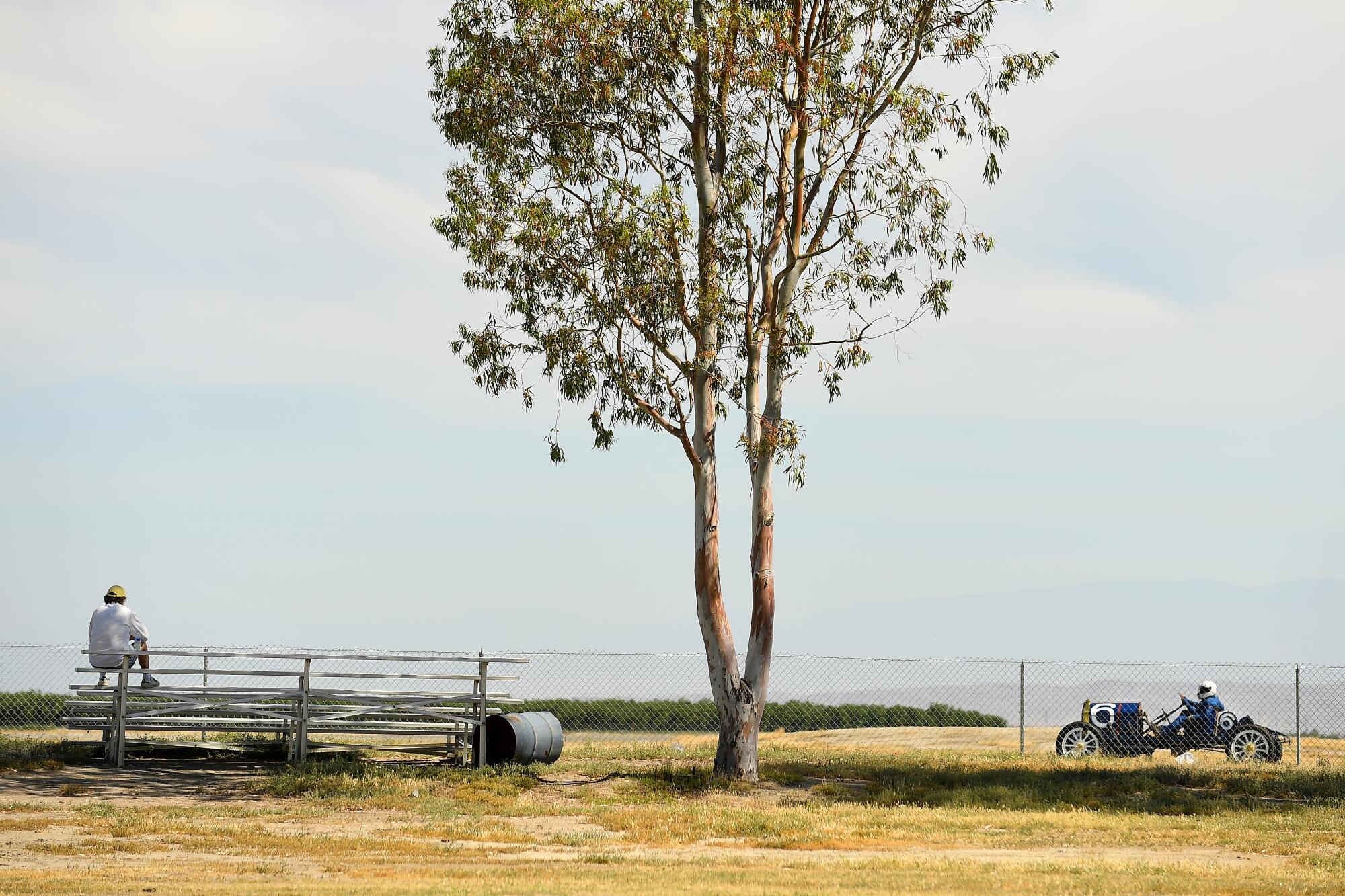 A lone spectator watches a vintage car drive by during a race at Buttonwillow Raceway in Buttonwillow, Calif., on Saturday. The Vintage Auto Racing Assn. held the races over the weekend as California slowly reopens after coronavirus shutdowns.