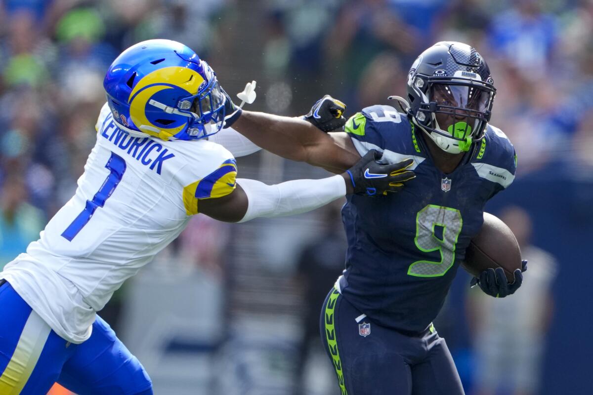 Seahawks running back Kenneth Walker III gives a straight arm to Rams cornerback Derion Kendrick.