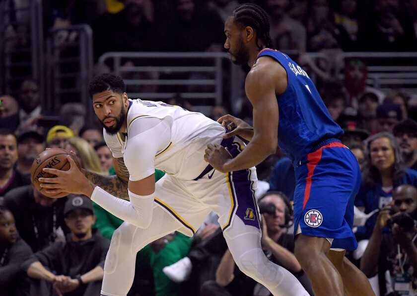 Lakers forward Anthony Davis controls the ball in front of Clippers forward Kawhi Leonard during the Lakers’ win at Staples Center on Sunday.