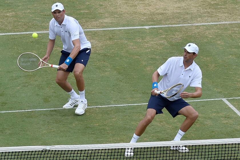 Bob Bryan plays a shot as his twin brother Mike leans out of his way during a David Cup double match Friday.