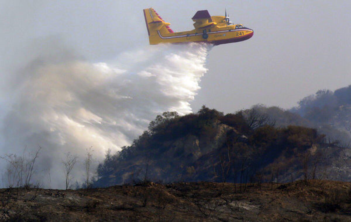 A water tanker, on lease from the Canadian province of Quebec, makes a drop on the Madre fire in Angeles National Forest above Azusa on Tuesday.