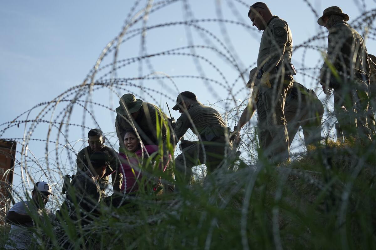People try to navigate around concertina wire.