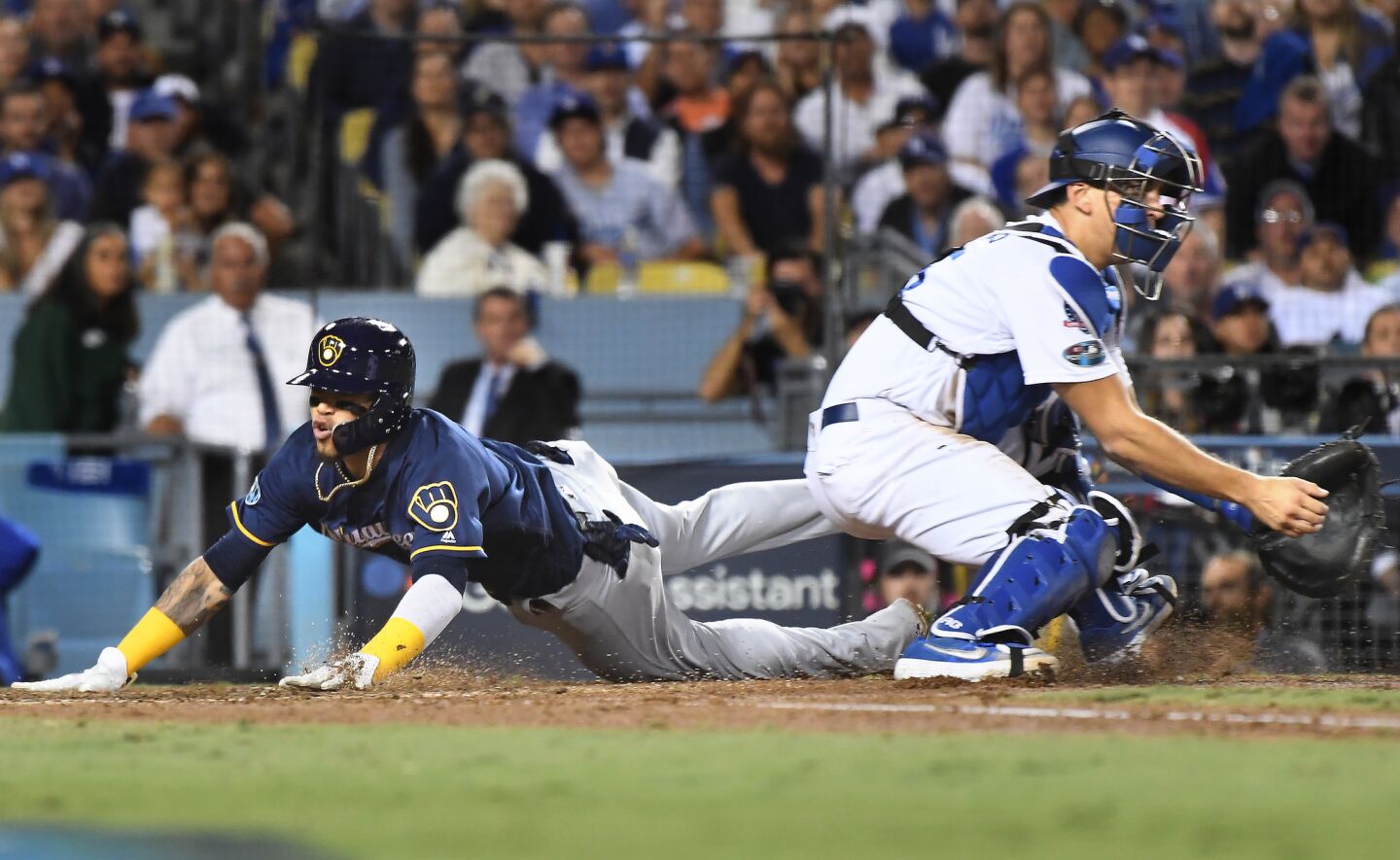 Brewers Orlando Arcia scores a run in fornt of Dodgers catcher Austin Barnes on a double by Domingo Santana in the 5th inning.