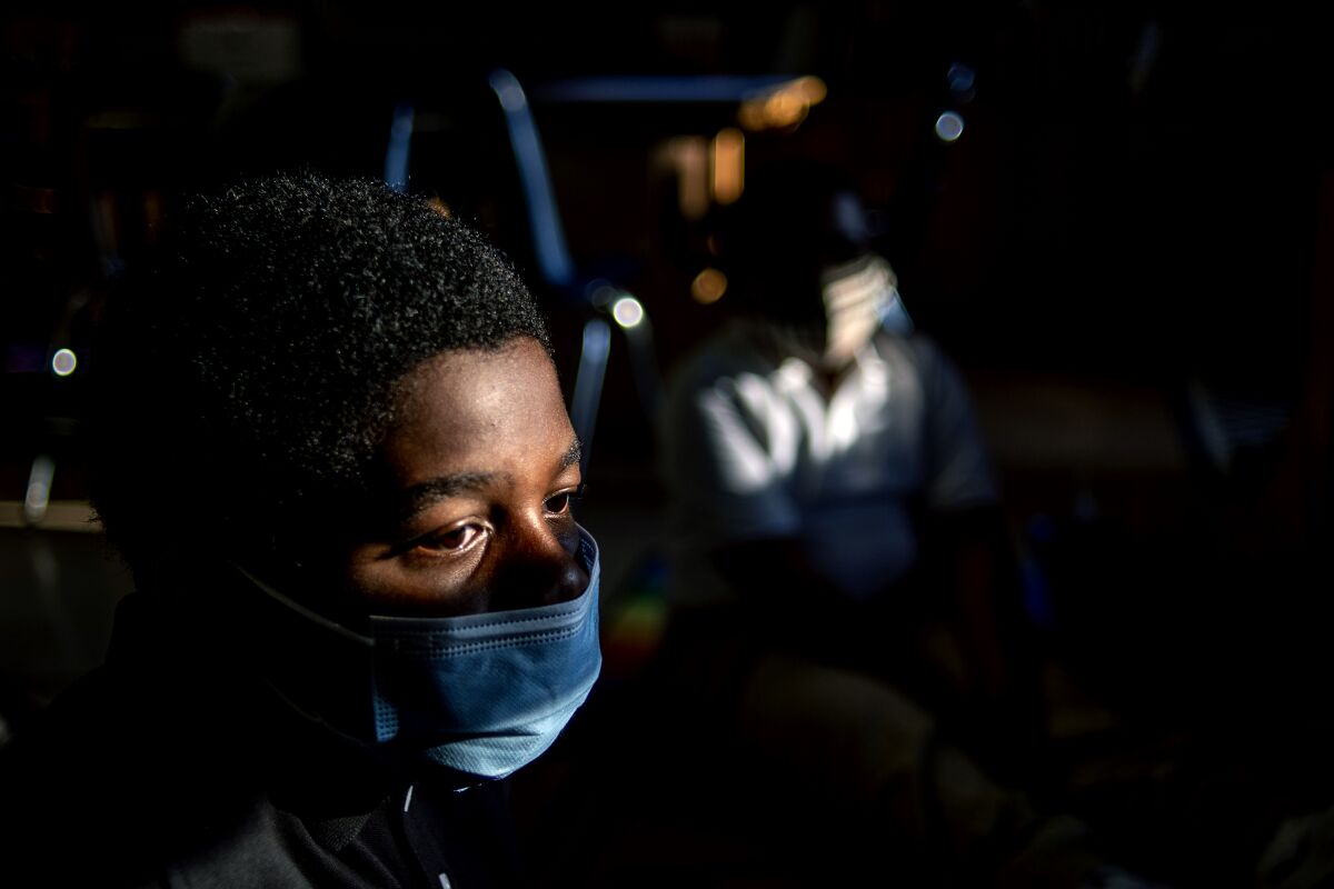 D'Monte Tally, 11, takes in the morning sunlight as he listens to sixth-grade teacher Krissy Gatz while learning new classroom rules on the first day of school on Wednesday, Aug. 4, 2021 at Freeman Elementary School in Flint, Mich. (Jake May/The Flint Journal via AP)