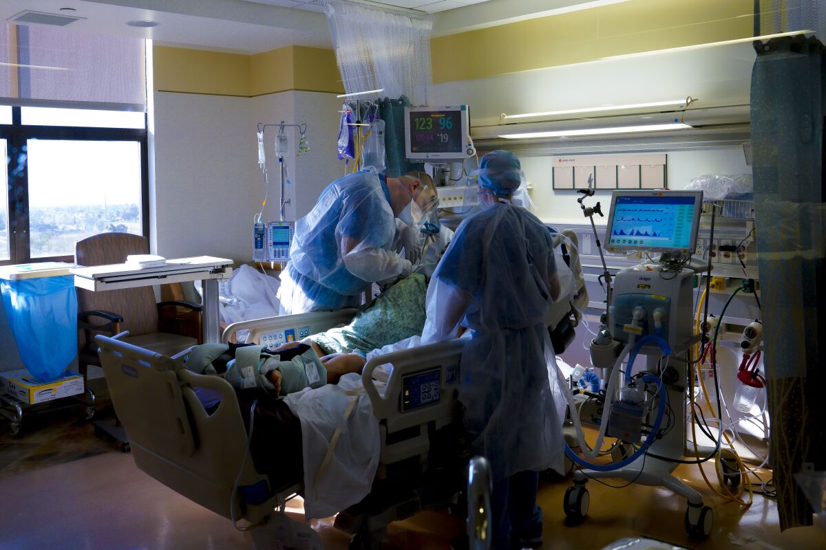 Two nurses tend to a patient in the intensive care unit