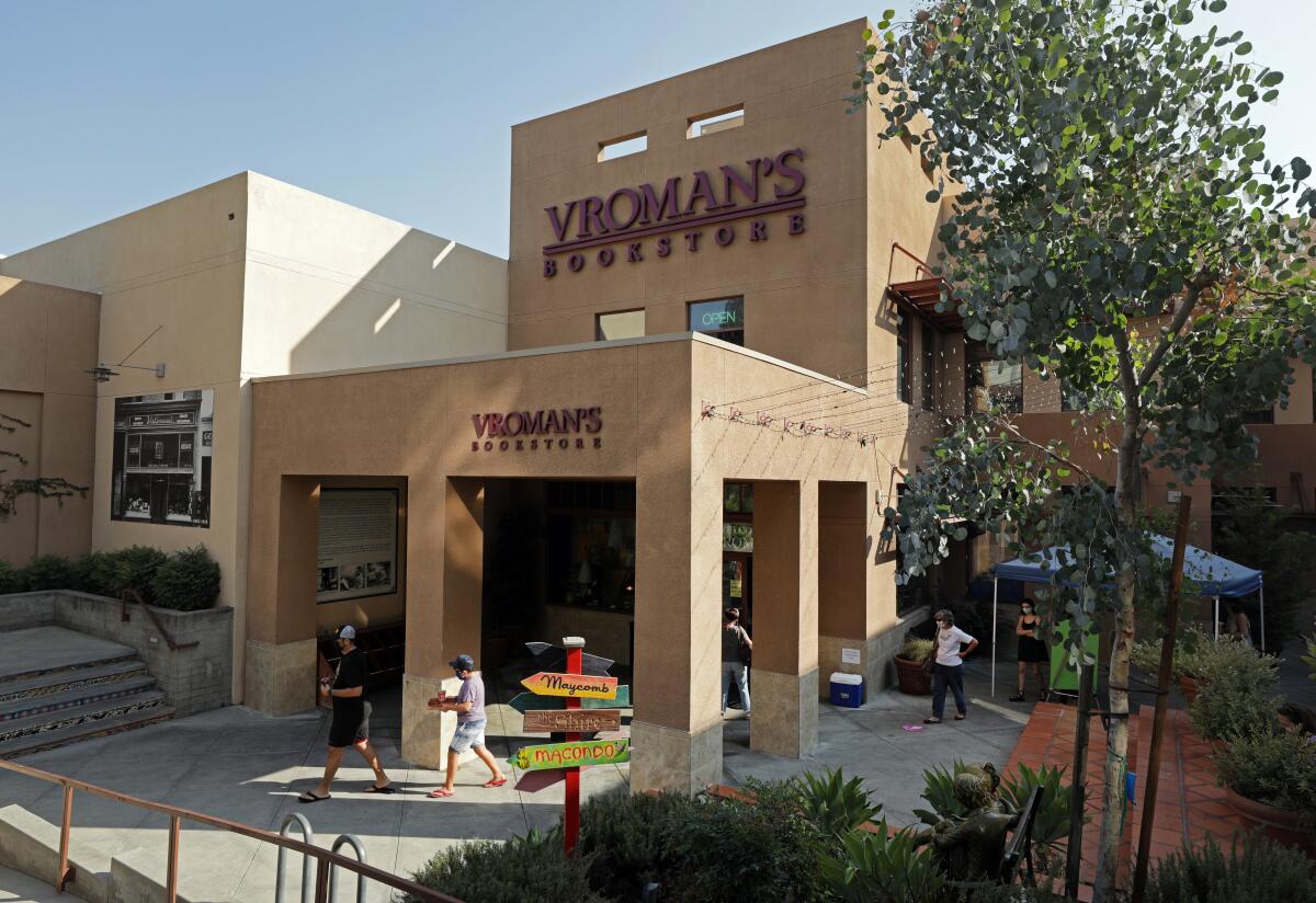 Customers walk by Vroman's Bookstore, a cube-like building with angular columns, painted a Spanish brown 
