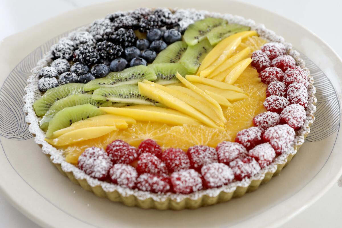 A matcha tart topped with raspberries, blueberries, blackberries, mango, kiwi and orange slices.