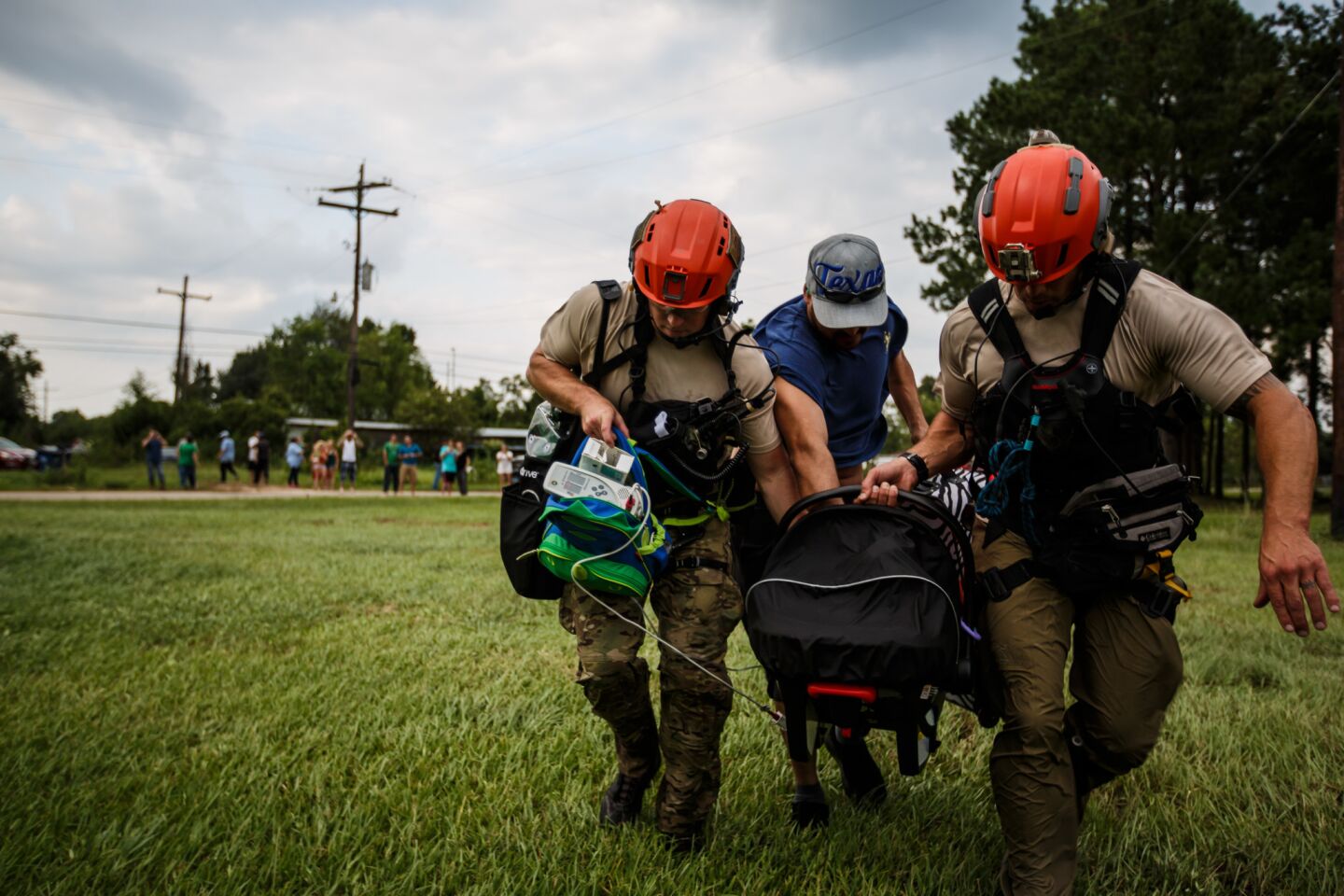 Members of the California Air National Guard 129th Rescue Wing, Senior Airman George McKenzie, left, and Master Sgt. Adam Vanhaaster, right, help a man carry his infant, who has a serious medical condition, to a hospital in Orange, Texas.