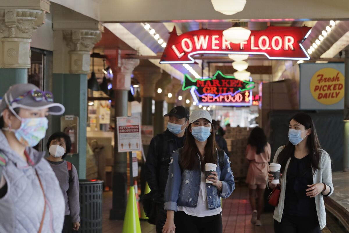 People wear masks as they walk through Pike Place Market in Seattle