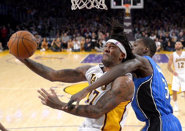 Lakers power forward Jordan Hill is fouled by Magic center Dewayne Dedmon on a layup in the second half Sunday at Staples Center.
