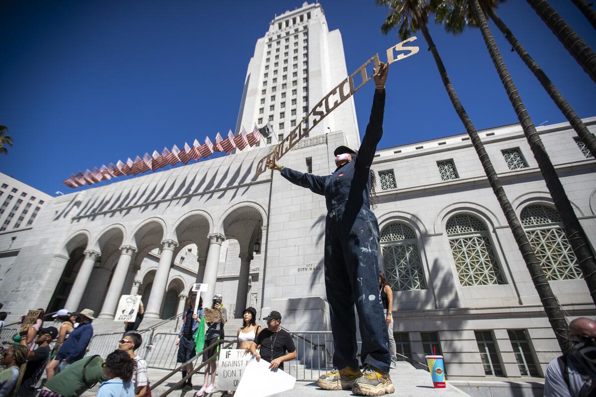 Chandrika Metivier, of Houston, Texas, stands high on Los Angeles City Hall steps holding a sign reading.