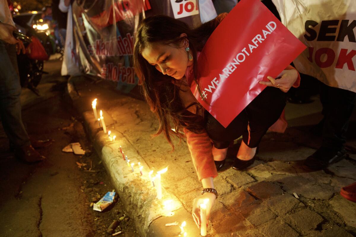 A woman lights candles near the site of an attack in Jakarta, Indonesia, where crowds gathered and chanted, "We are not afraid," on Jan. 15, 2016.