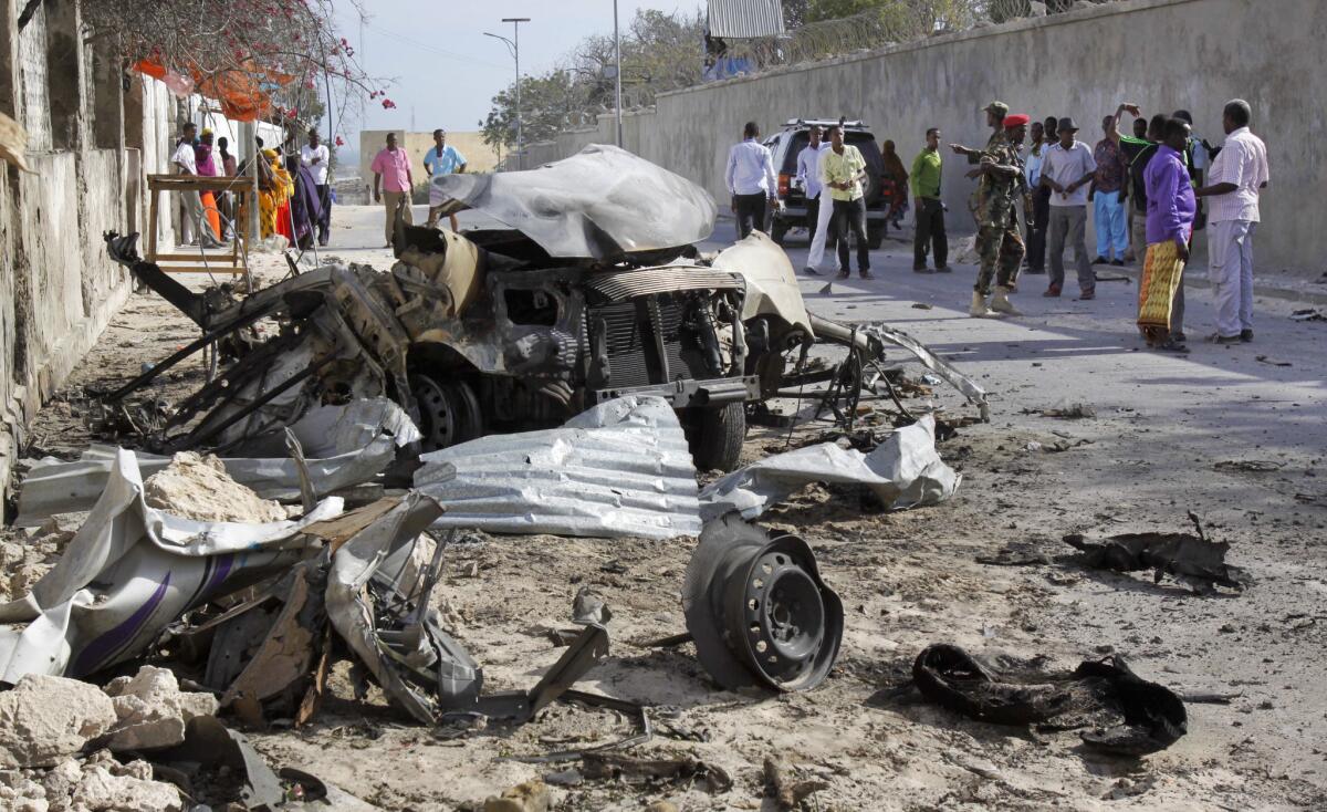 Somalis gather near the wreckage of one of two car bombs used in an attack on the presidential compound in Mogadishu. Nine militants and two Somali government officials were killed; Somali President Hassan Sheik Mohamud was not harmed.