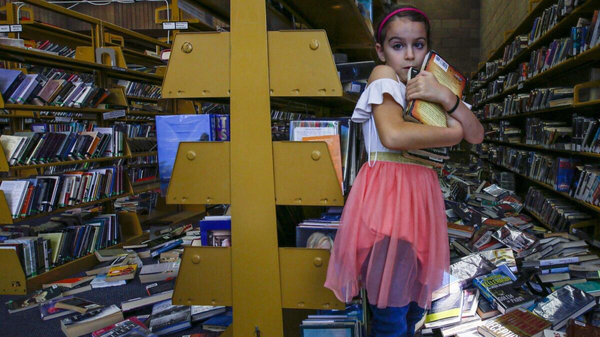 Zoe Pineda, 7, helps clean up the Ridgecrest Branch Library damaged by the Southern California earthquake.