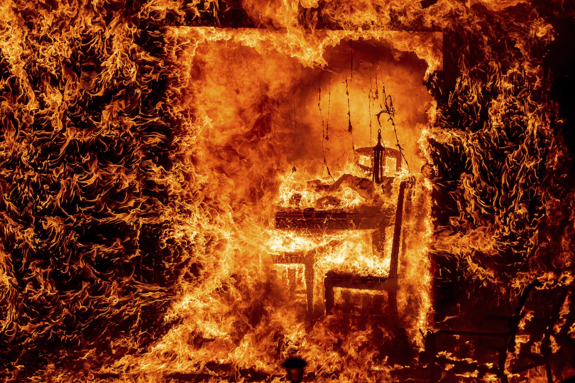 Flames engulf a chair inside a burning home.