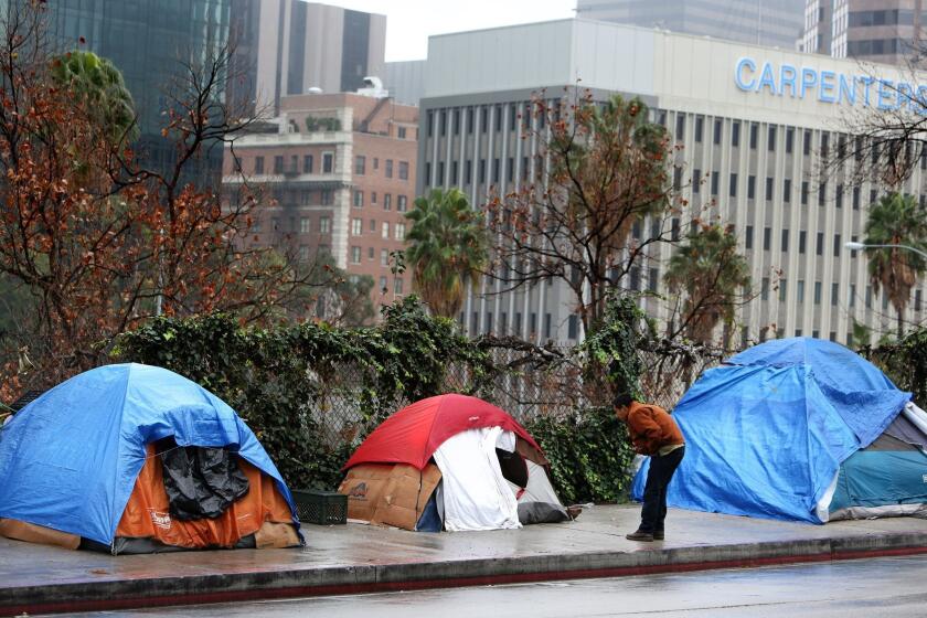 Homeless people shelter from the rain under camping tents in downtown Los Angeles on Tuesday, Dec. 22, 2015.