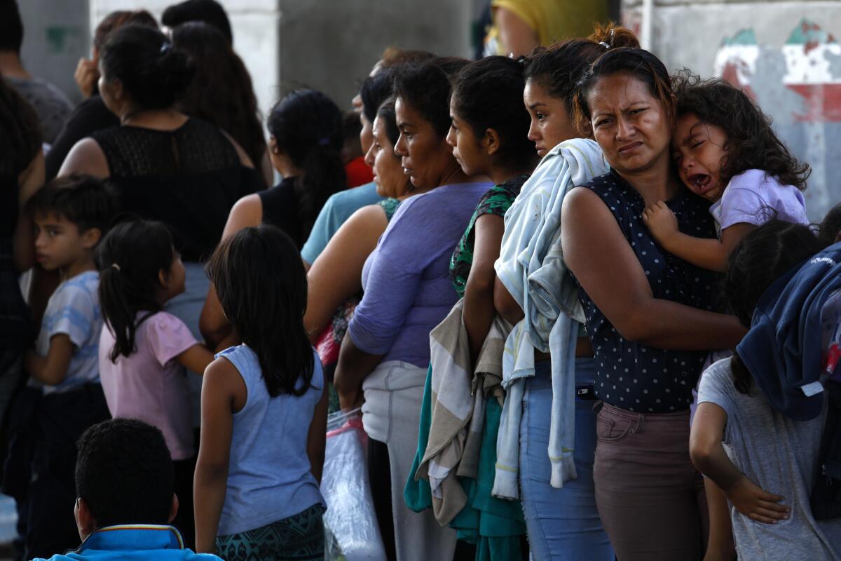 Asylum seekers wait in the parking lot of an immigration checkpoint in Nuevo Laredo, Mexico, on Aug. 1.