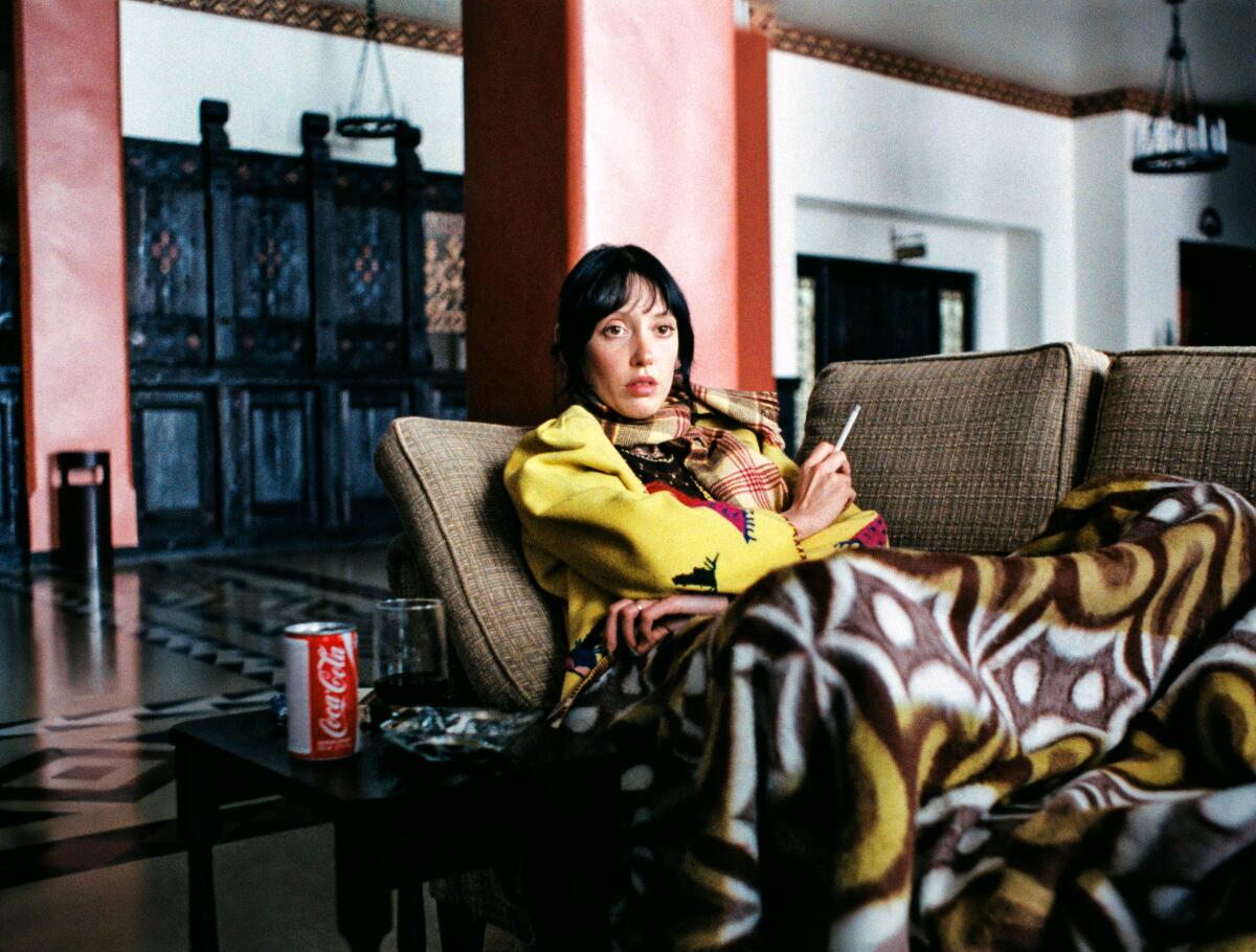 A woman watches TV in a large, ghostly lobby.