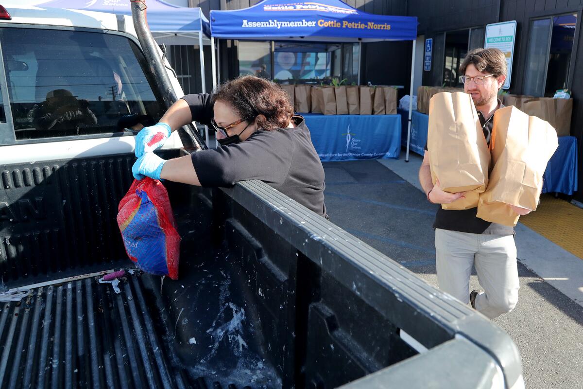 Alice Tutunjian, left, Share Our Selves Foundation staff member, loads a turkey in a truck on Tuesday in Costa Mesa.