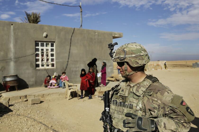FILE - In this Jan. 27, 2018, file photo, U.S. Army soldiers speak to families in rural Anbar on a reconnaissance patrol near a coalition outpost in western Iraq. Iraqs president has slammed comments by U.S. President Donald Trump who he says he wants to keep U.S. troops in Iraq to watch Iran. Barham Salih said Monday, Feb. 4, 2019 that Trump did not ask Iraqs permission for American troops stationed there to watch Iran, describing his comments as strange.(AP Photo/Susannah George, File)