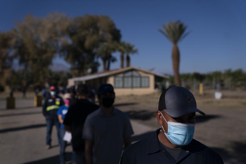 Jornaleros agrícolas hispanos hacen fila para recibir la vacuna de Pfizer-BioNTech contra el COVID-19 el jueves 21 de enero de 2021, en Mecca, California. (AP Foto/Jae C. Hong)