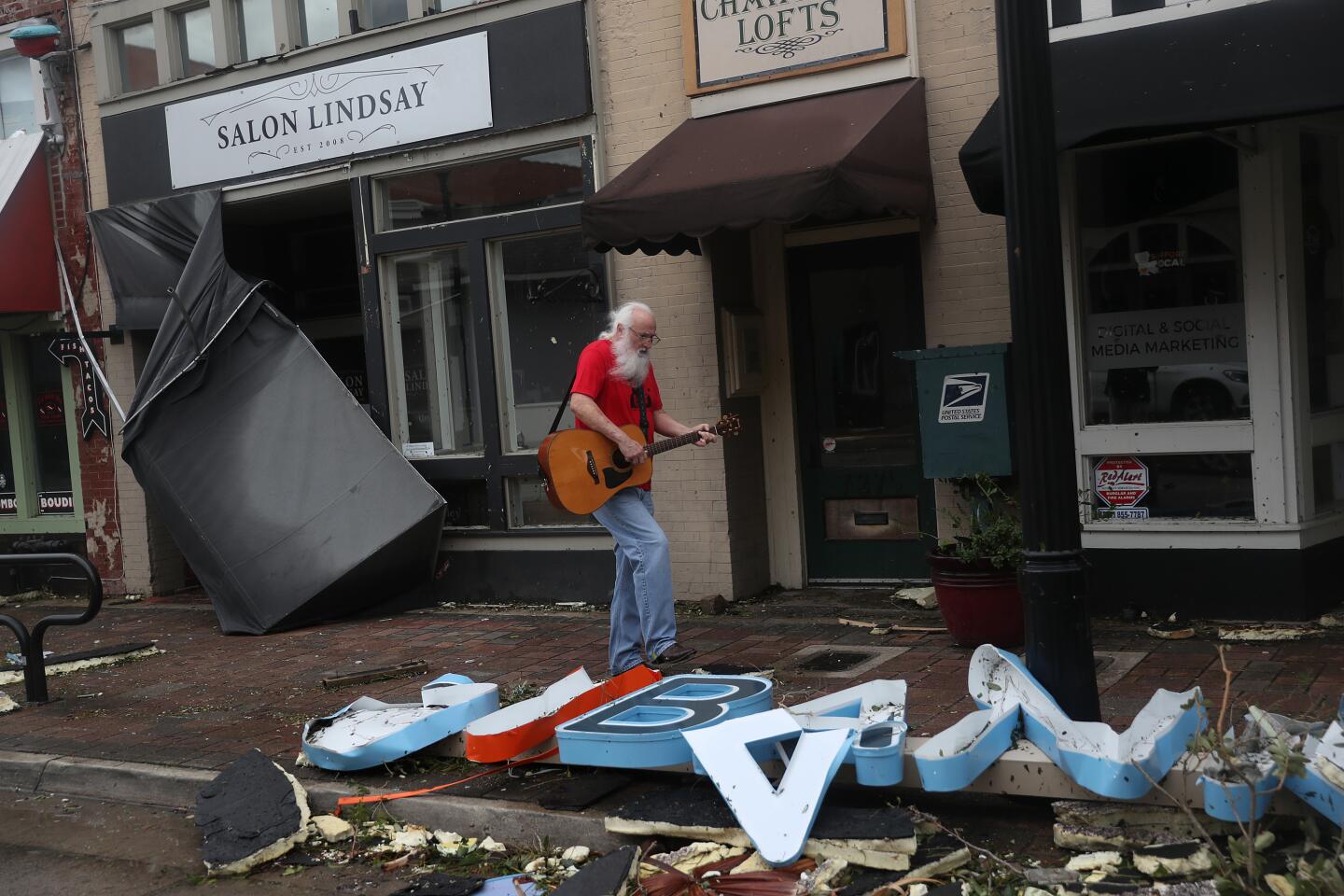 Mitch Pickering plays his guitar while inspecting damage in downtown Lake Charles, La.