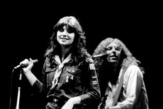 Black and white photo of Linda Ronstadt performing with guitarist Waddy Wachtel behind her