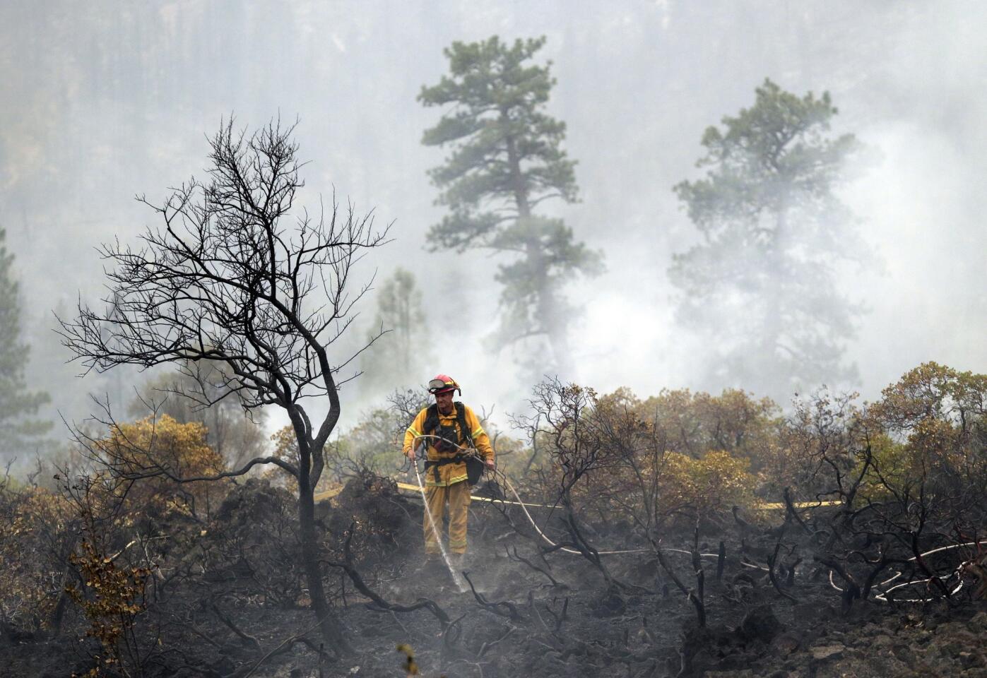 A firefighter douses hot spots left behind by the Eiler fire along California 89 near Burney, Calif.