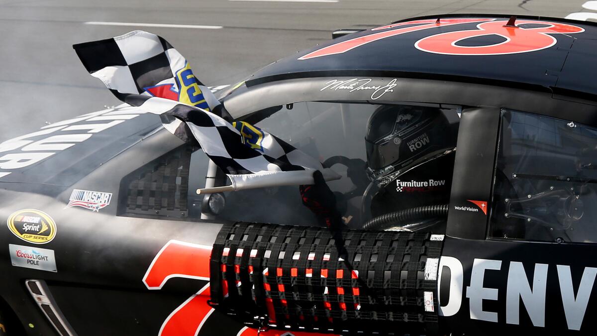 Martin Truex Jr. celebrates with the checkered flag after winning Sunday's NASCAR Sprint Cup Series race at Pocono Raceway on June 7, 2015.