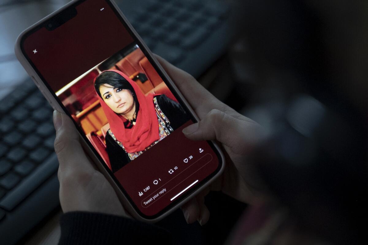 A woman looks at a picture of Mursal Nabizada on her mobile phone