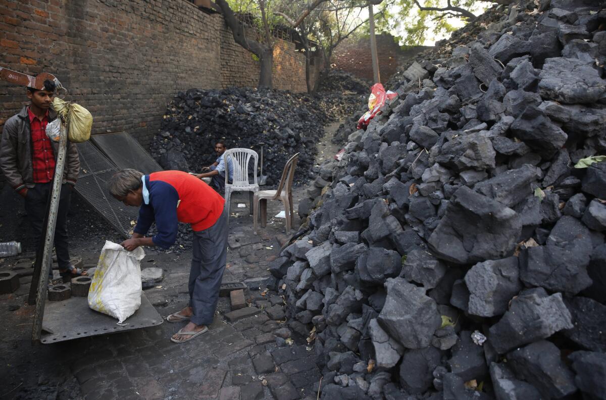 An Indian coal vendor weighs coal for a customer in Lucknow on Dec. 3.