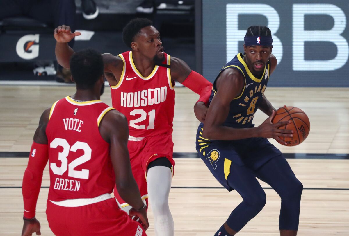 Indiana Pacers forward Justin Holiday (8) drives to the basket against Houston Rockets guard Michael Frazier (21) and forward Jeff Green (32) during the second half of an NBA basketball game Wednesday, Aug. 12, 2020, in Lake Buena Vista, Fla. (Kim Klement/Pool Photo via AP)